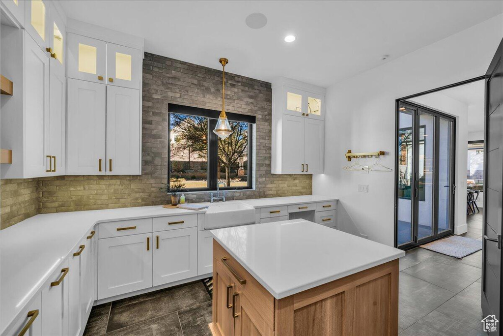 Kitchen featuring healthy amount of natural light, tasteful backsplash, light countertops, white cabinets, and recessed lighting