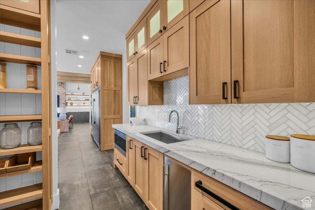 Kitchen with stainless steel appliances, decorative backsplash, light stone counters, recessed lighting, and glass insert cabinets