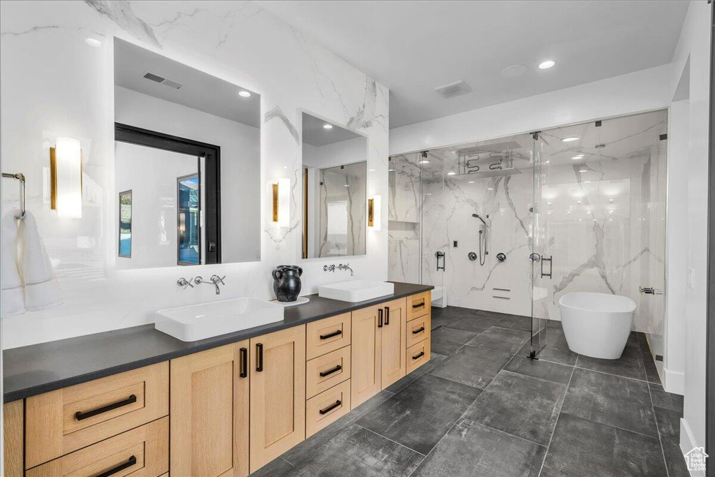 Bathroom with double vanity, a marble finish shower, a freestanding tub, tile walls, and recessed lighting