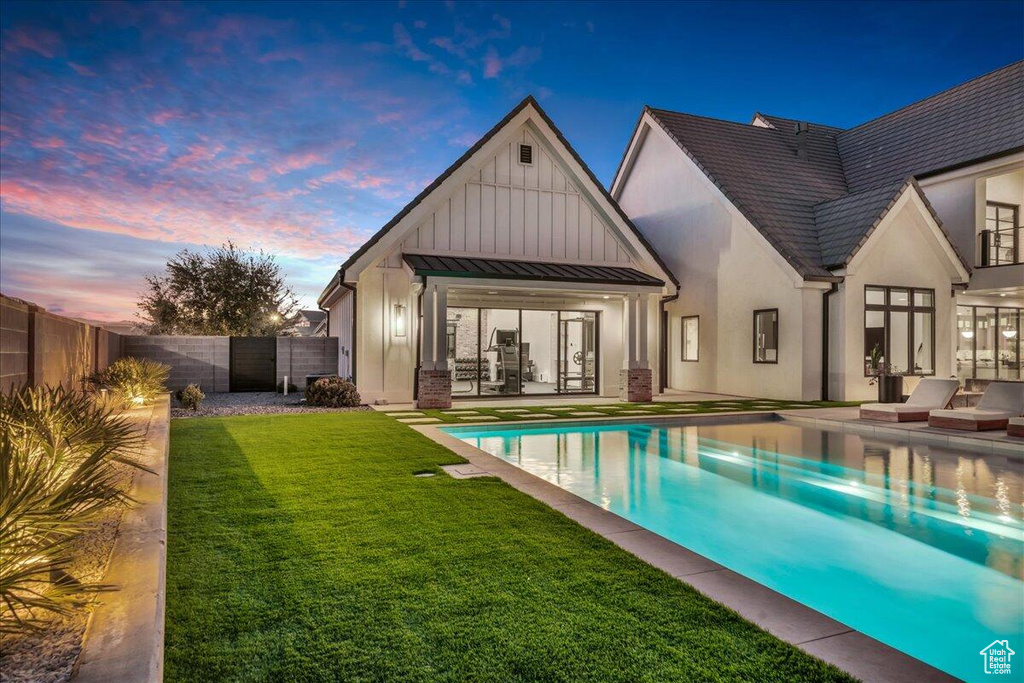 Back of property at dusk featuring board and batten siding, a patio area, a fenced backyard, and a standing seam roof
