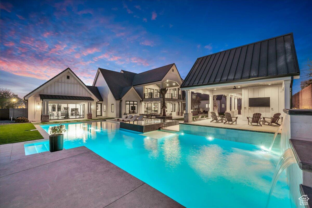 Pool at dusk with an outdoor hangout area, an exterior structure, an outdoor pool, and a patio area