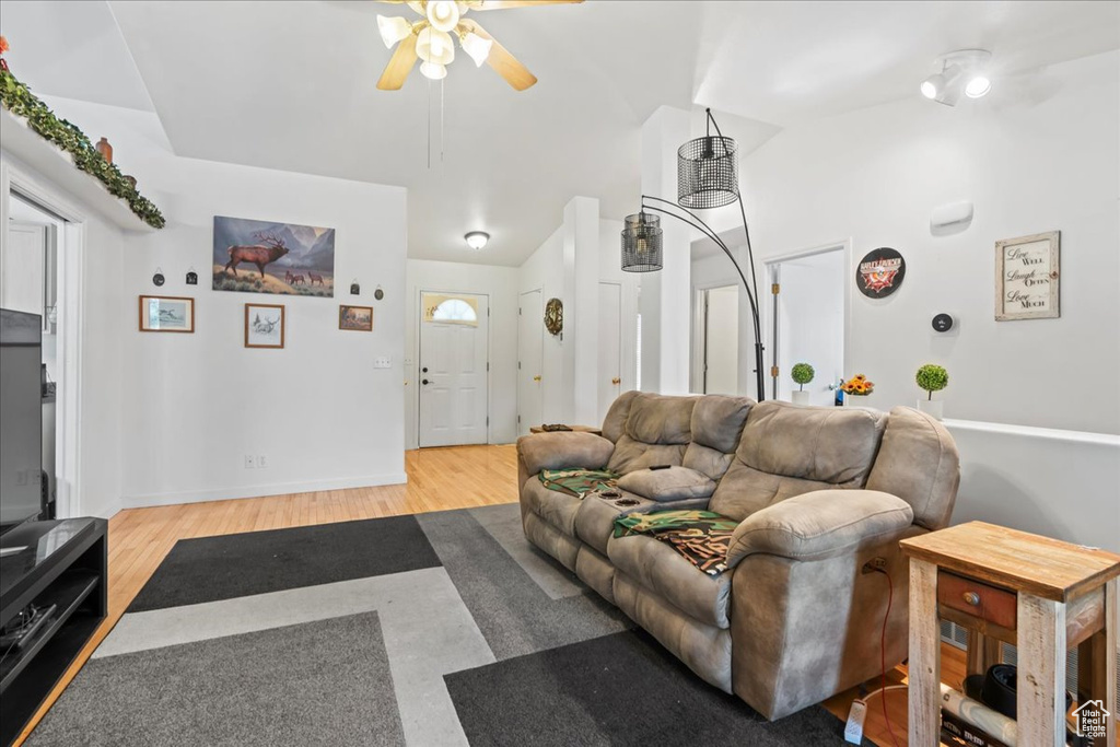 Living area with a ceiling fan, light wood finished floors, and vaulted ceiling