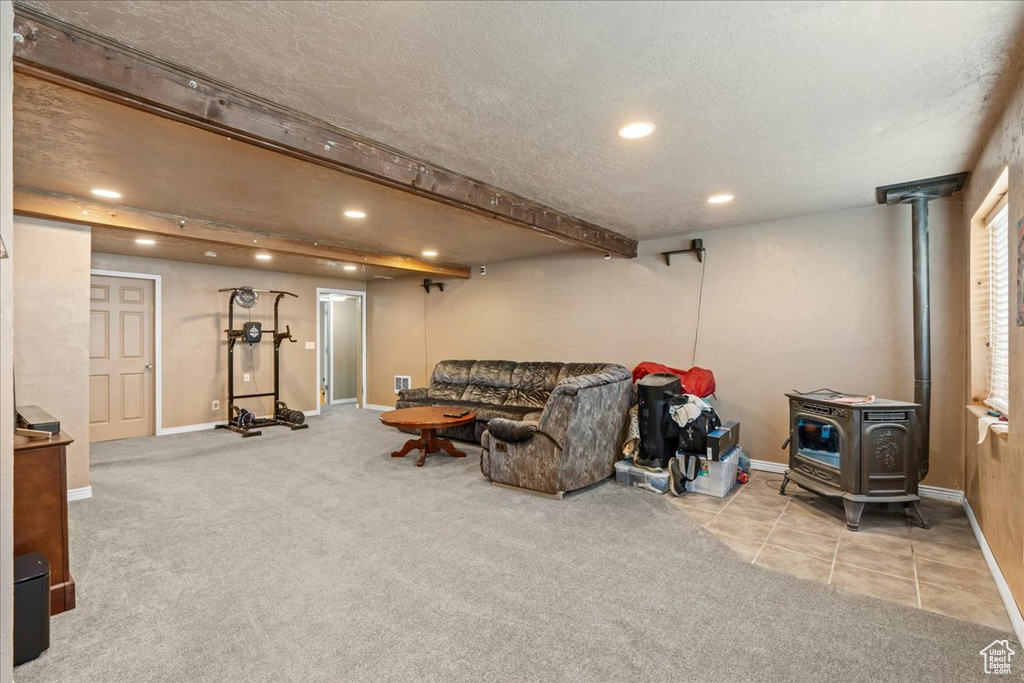 Living area with a wood stove, recessed lighting, carpet floors, and a textured ceiling