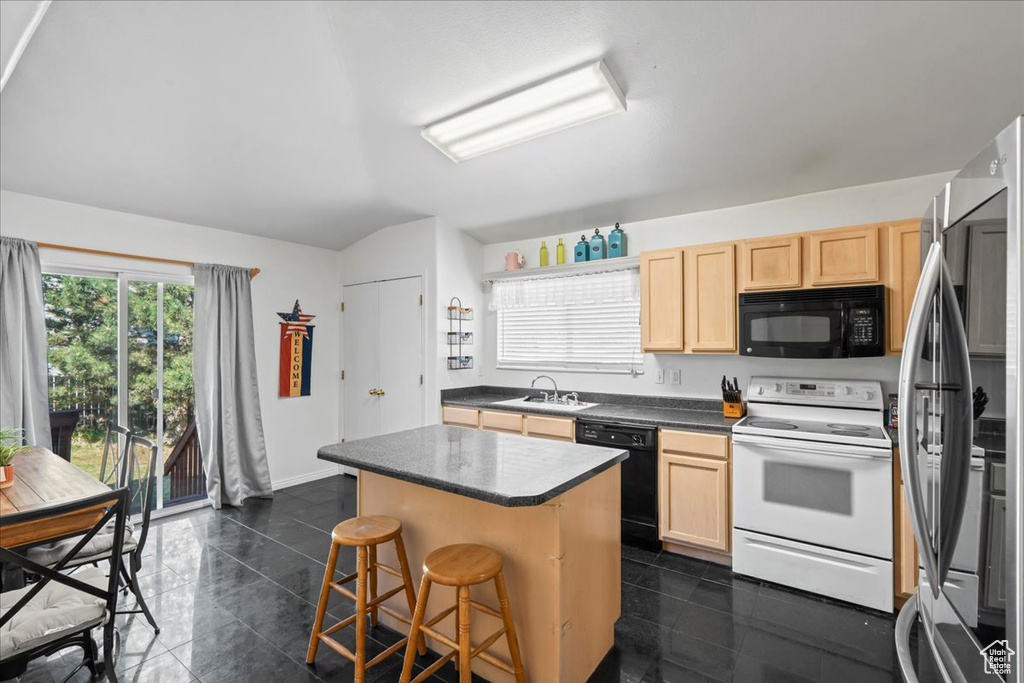 Kitchen with black appliances, light brown cabinets, a kitchen island, and a kitchen breakfast bar