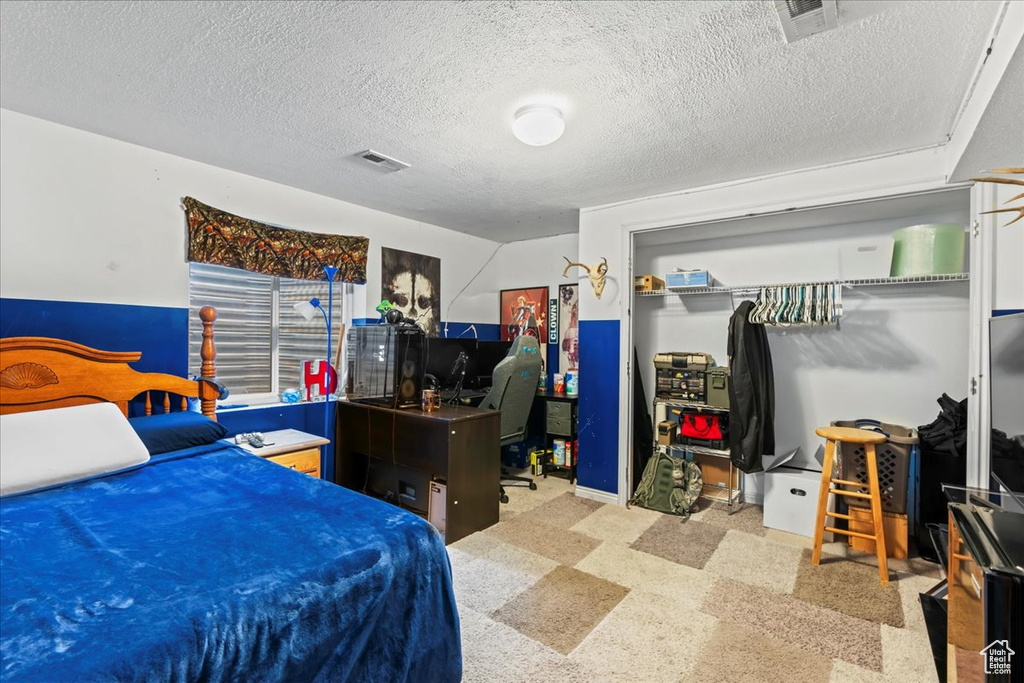 Bedroom featuring an office area, a closet, and a textured ceiling