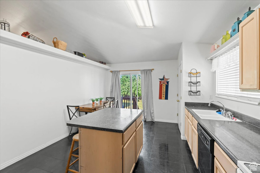 Kitchen featuring light brown cabinetry, a kitchen breakfast bar, and dishwasher
