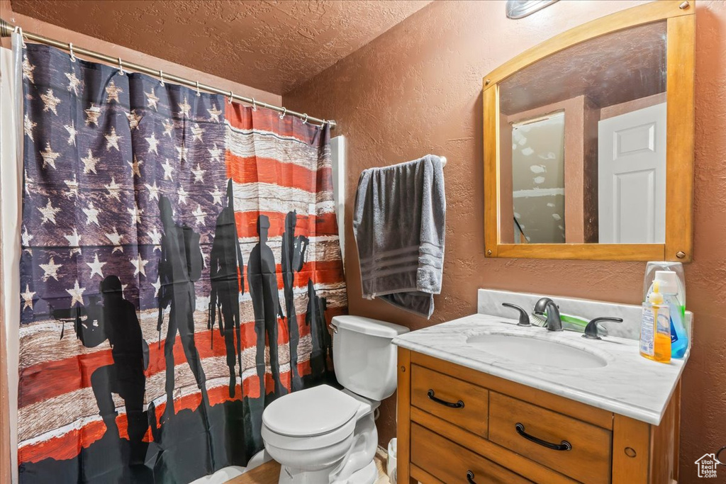 Bathroom featuring a textured wall, vanity, a textured ceiling, and a shower with shower curtain