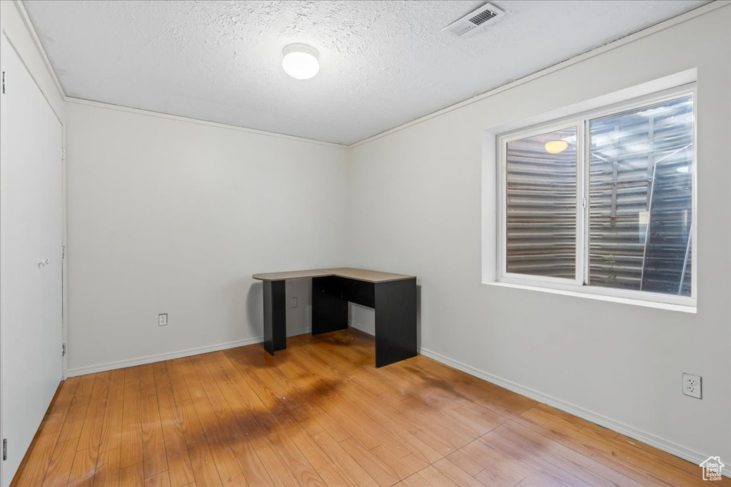 Spare room featuring light wood finished floors and a textured ceiling