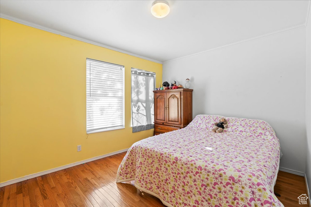 Bedroom with ornamental molding and wood finished floors