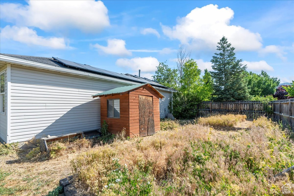 View of side of property with a storage shed and roof mounted solar panels