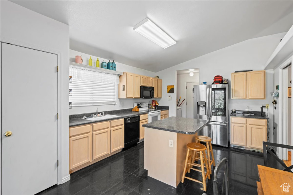 Kitchen featuring black appliances, light brown cabinets, vaulted ceiling, and dark countertops