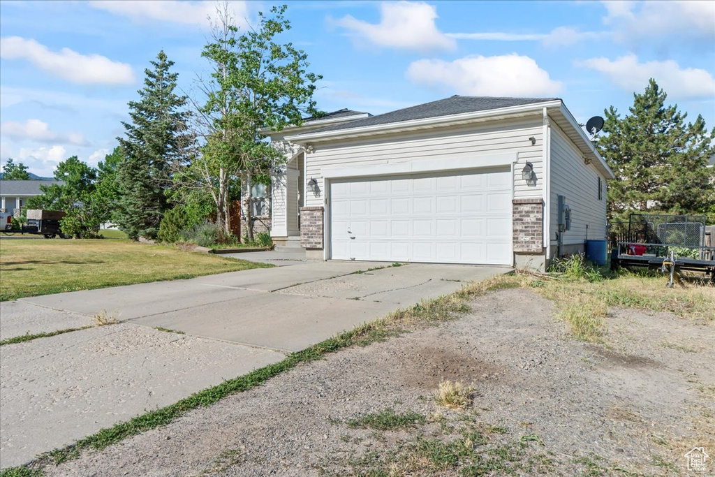 View of front facade featuring driveway, a garage, a front yard, and brick siding