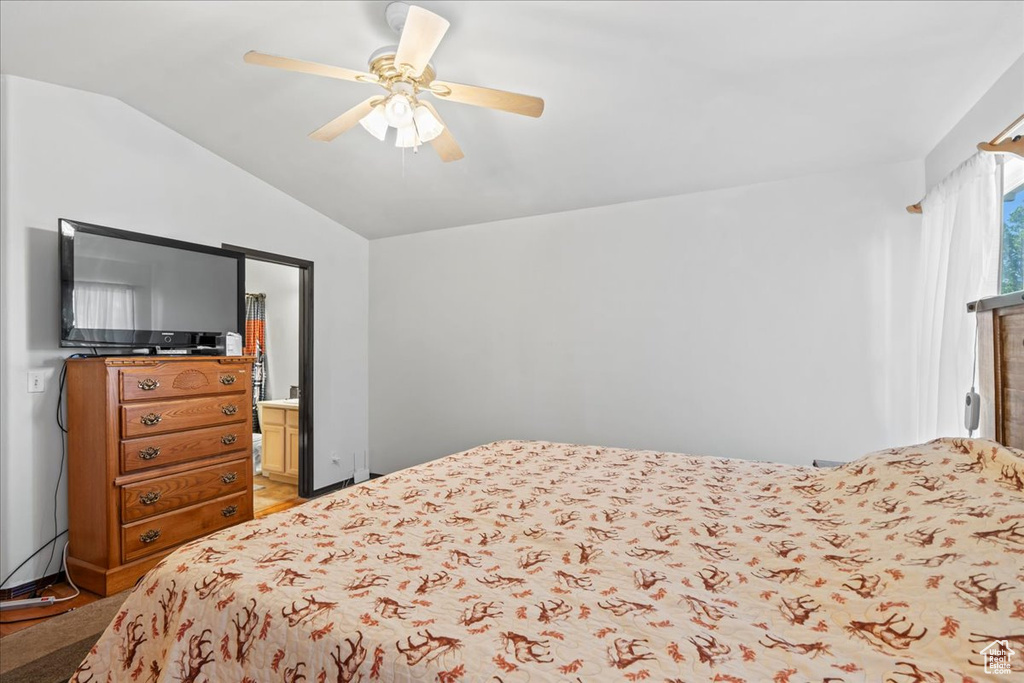 Bedroom with vaulted ceiling, a ceiling fan, light wood finished floors, and connected bathroom