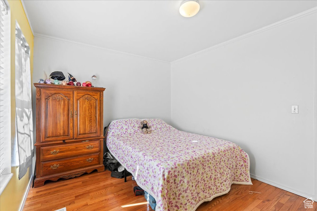 Bedroom with ornamental molding and light wood finished floors