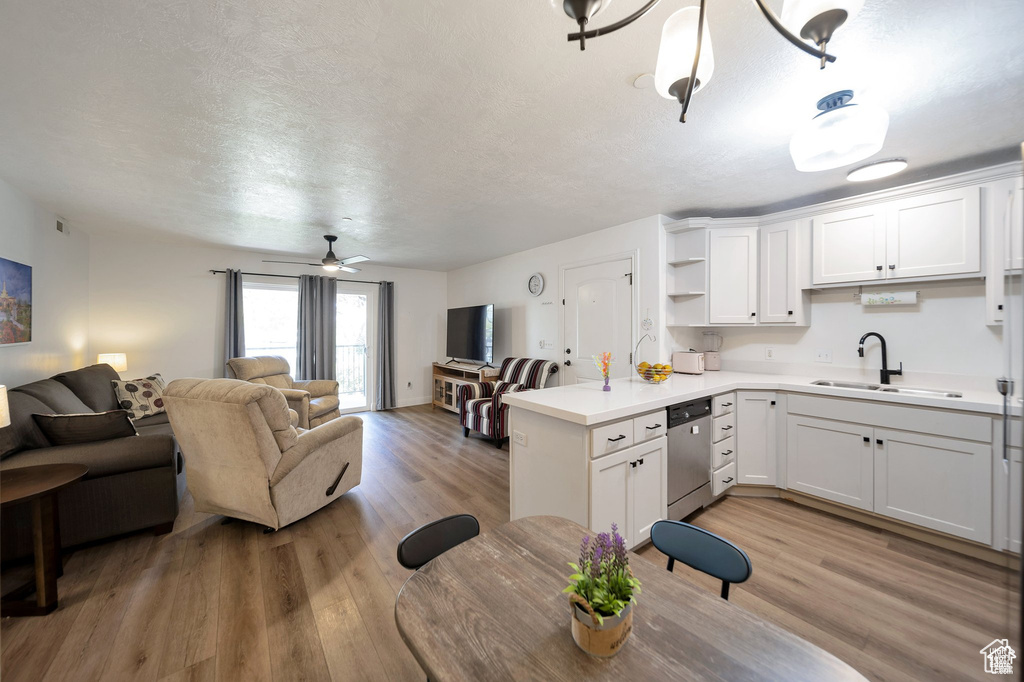 Kitchen featuring dishwasher, open floor plan, white cabinetry, light countertops, and light wood-style floors