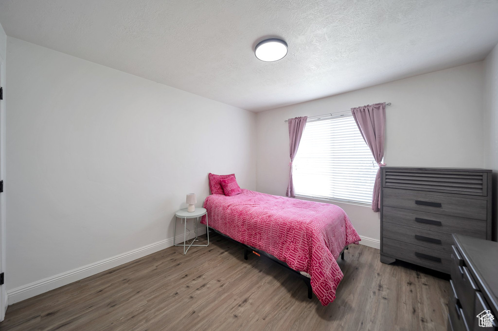 Bedroom with wood finished floors and a textured ceiling