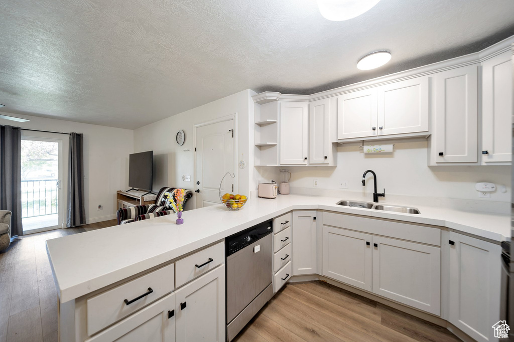 Kitchen featuring dishwasher, a peninsula, open floor plan, light wood-style flooring, and white cabinetry