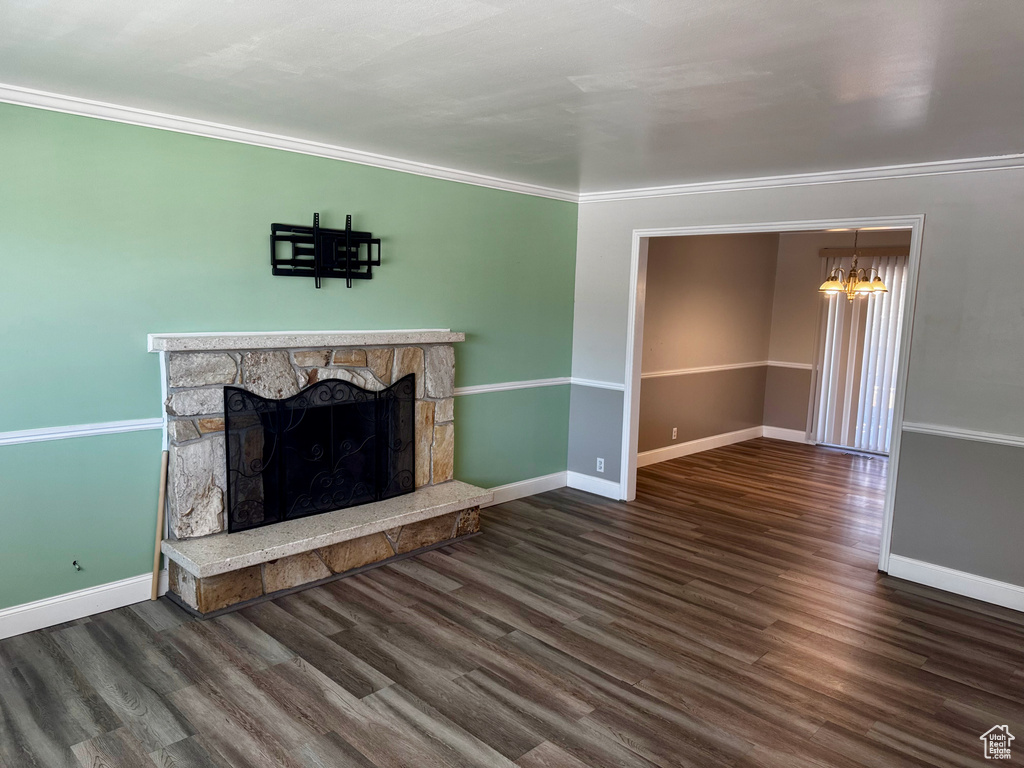 Unfurnished living room with a chandelier, ornamental molding, a fireplace, and wood finished floors