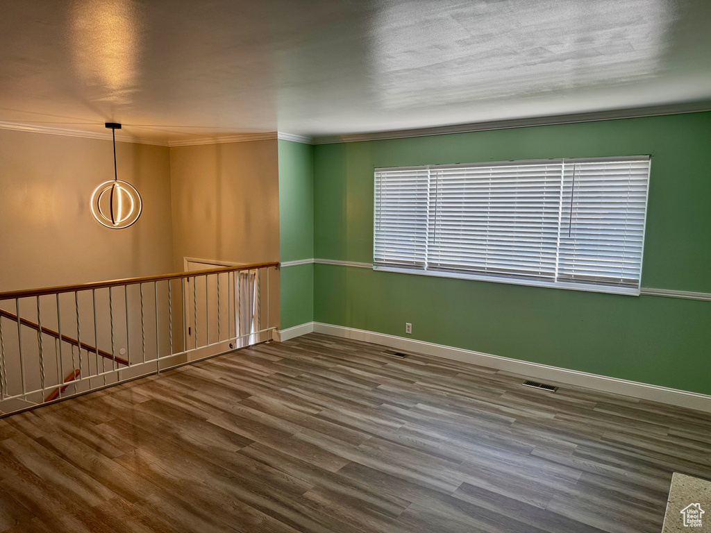 Unfurnished room with wood finished floors and crown molding