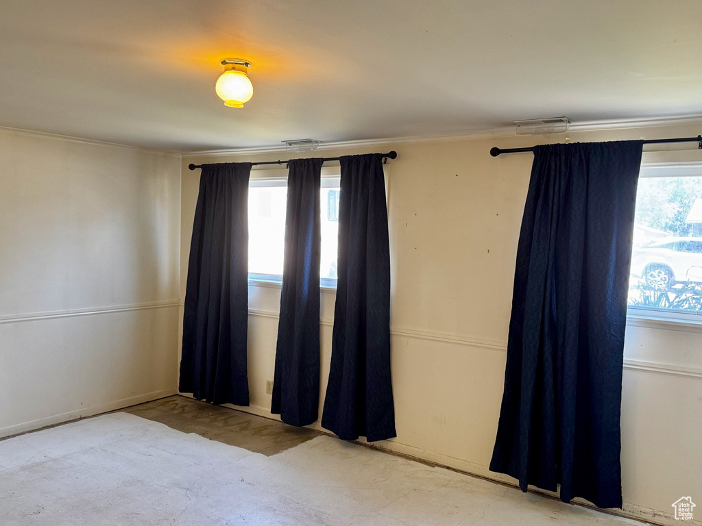Carpeted empty room featuring crown molding and baseboards