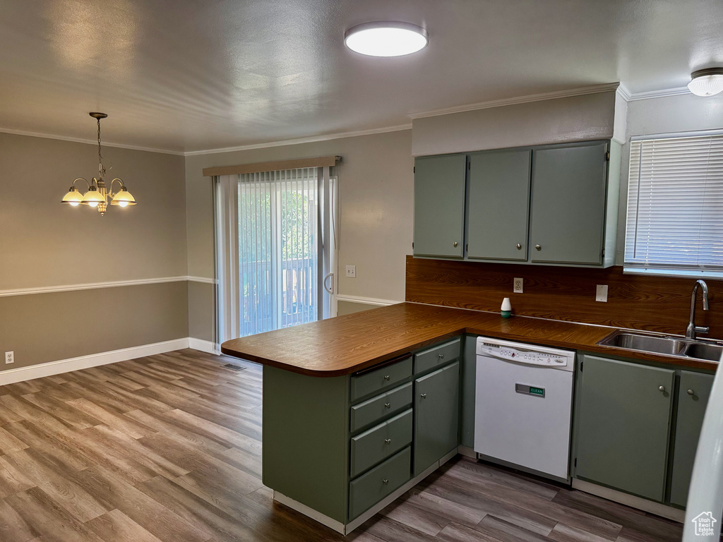 Kitchen featuring white dishwasher, green cabinetry, a peninsula, a chandelier, and wood finished floors