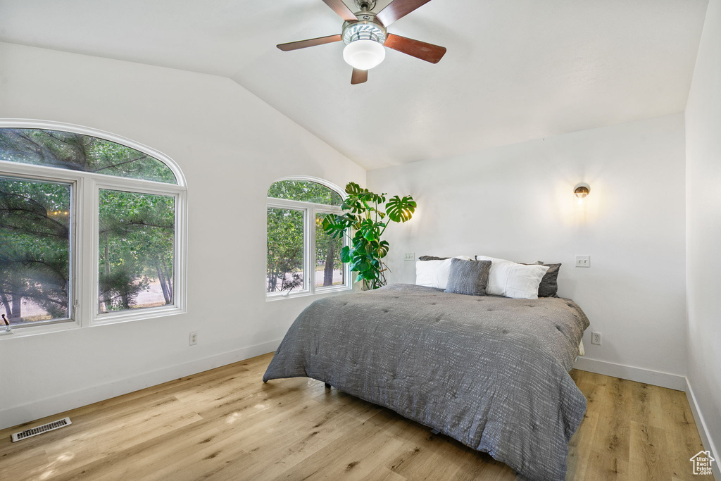Bedroom with vaulted ceiling, wood finished floors, and ceiling fan