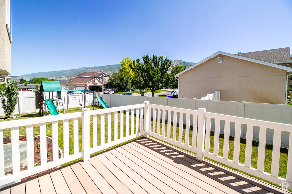 Deck with a playground, a mountain view, a fenced backyard, and a residential view