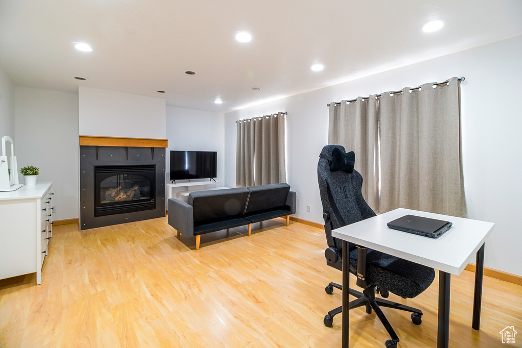 Office with light wood-type flooring, recessed lighting, and a glass covered fireplace