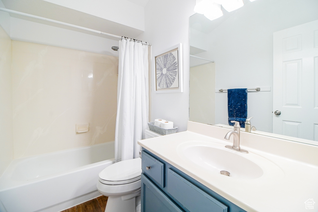 Bathroom with vanity, shower / bath combo with shower curtain, and wood finished floors