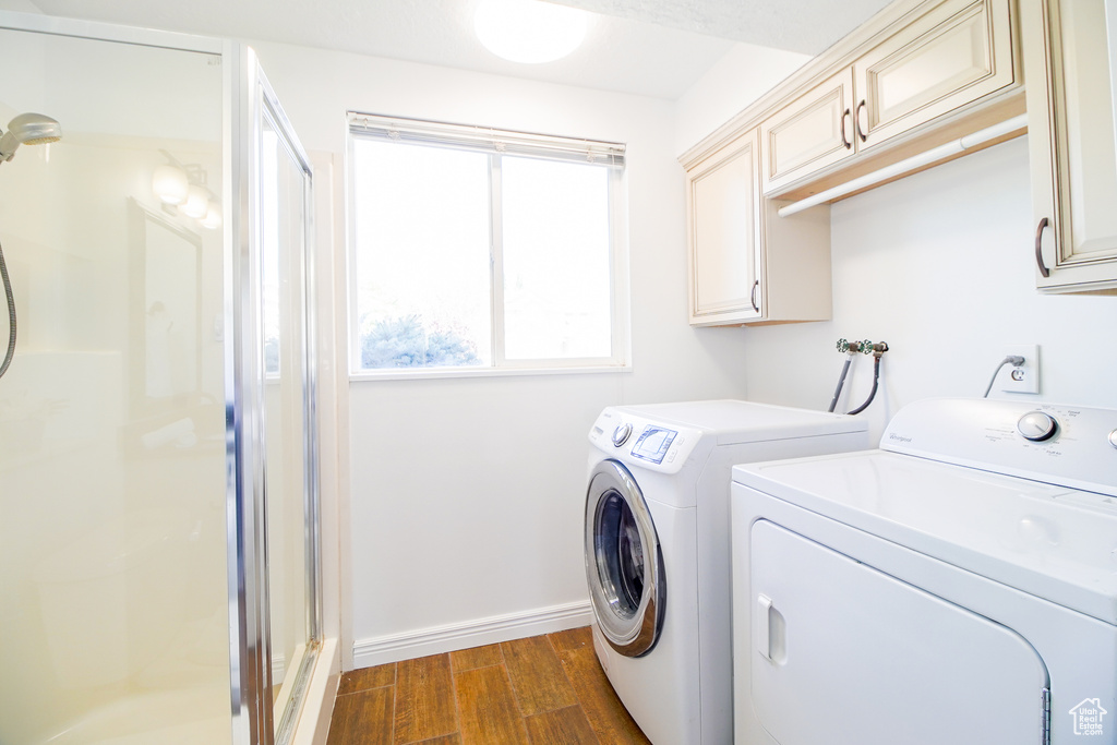 Laundry room featuring washer and clothes dryer, cabinet space, and dark wood-style flooring