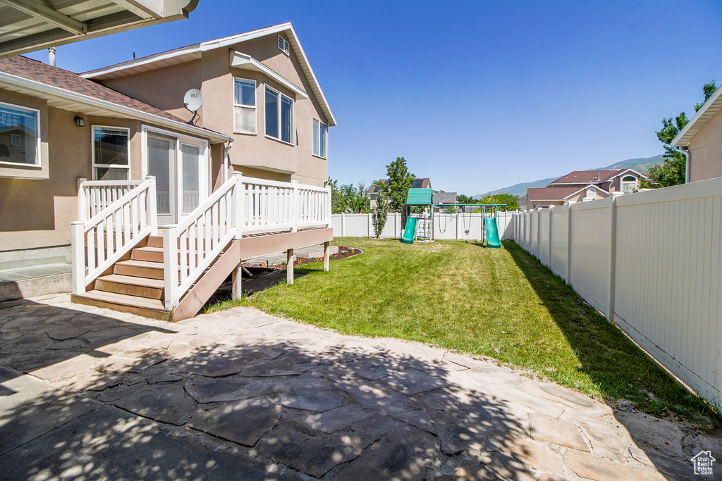 Fenced backyard with a playground and a patio area