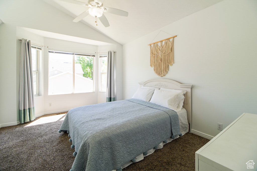 Bedroom with dark carpet, lofted ceiling, and a ceiling fan