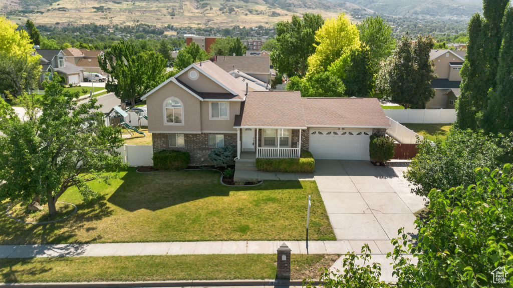 View of front of home with driveway, a garage, brick siding, a mountain view, and a porch
