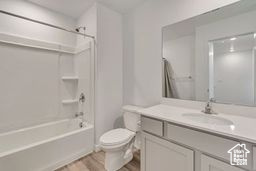 Full bath featuring vanity, wood finished floors, and washtub / shower combination