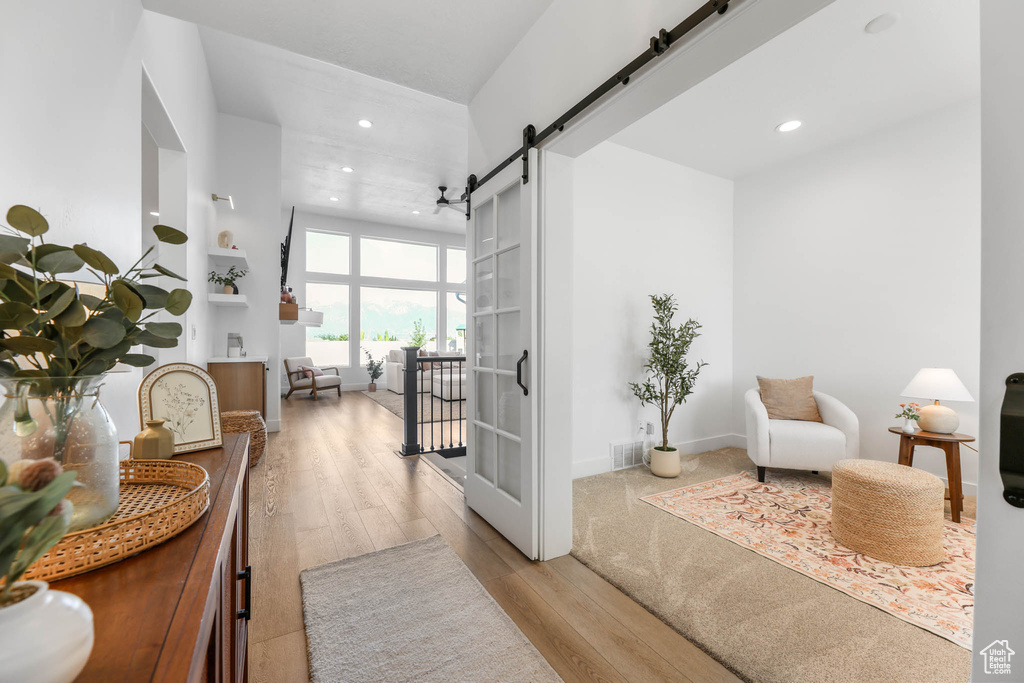 Hall with a barn door, recessed lighting, and wood finished floors