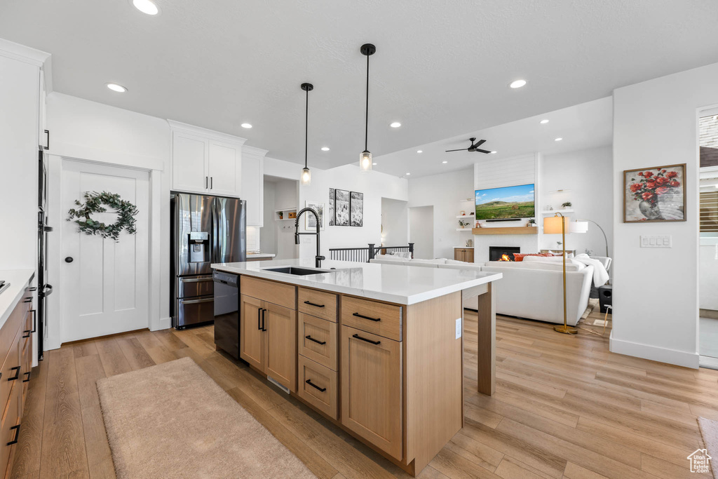 Kitchen featuring a lit fireplace, stainless steel fridge, light wood-type flooring, a kitchen breakfast bar, and recessed lighting