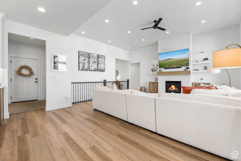 Living area with a ceiling fan, light wood-style floors, recessed lighting, and a fireplace
