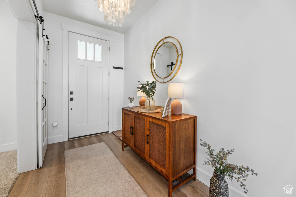 Entrance foyer with a chandelier, light wood-type flooring, and a barn door