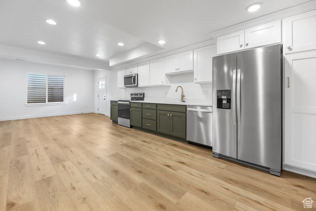 Kitchen featuring appliances with stainless steel finishes, white cabinets, recessed lighting, light countertops, and light wood-style floors