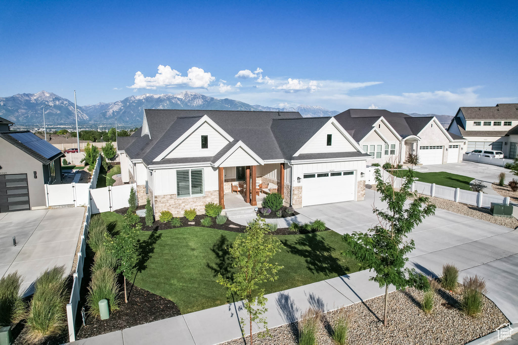 Modern inspired farmhouse featuring stone siding, a gate, driveway, a mountain view, and a garage