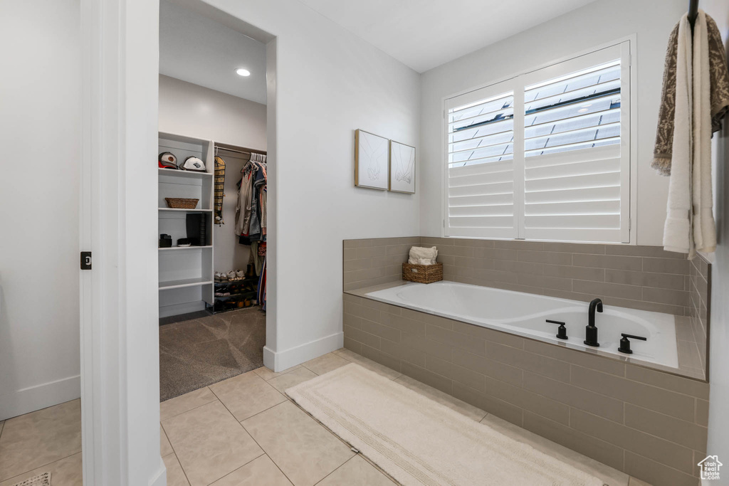 Full bathroom featuring a garden tub, a walk in closet, and tile patterned flooring