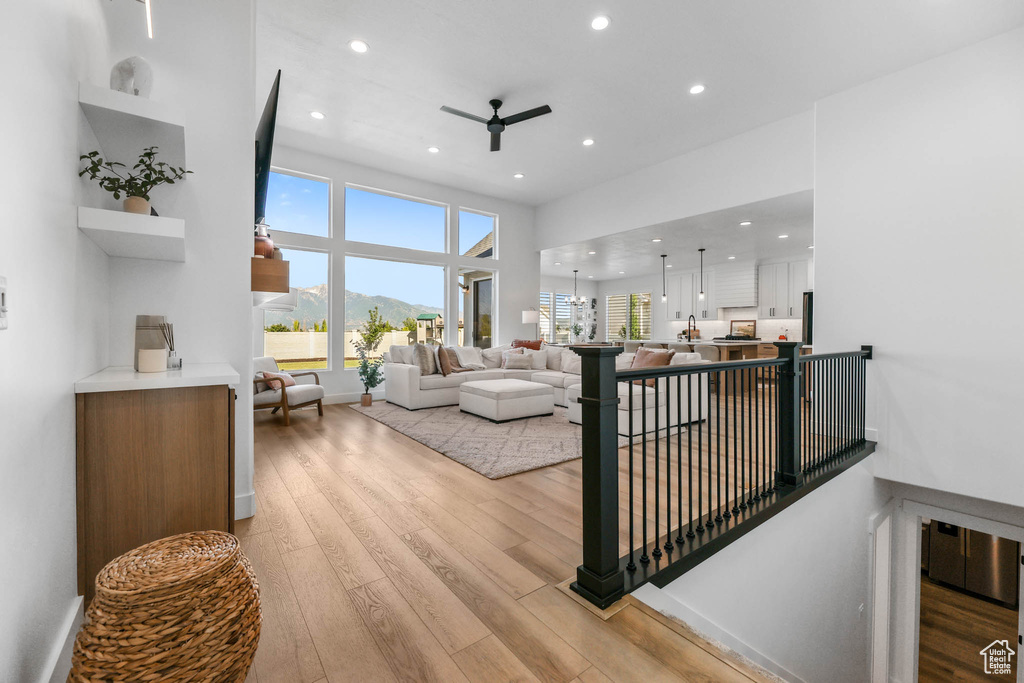 Living room with ceiling fan, light wood-style floors, and recessed lighting