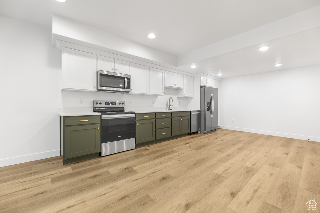 Kitchen featuring appliances with stainless steel finishes, recessed lighting, white cabinets, light countertops, and green cabinetry