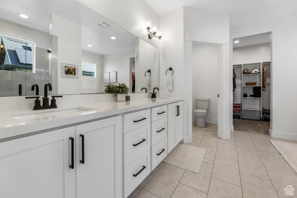 Full bathroom featuring double vanity, a spacious closet, a stall shower, recessed lighting, and tile patterned floors