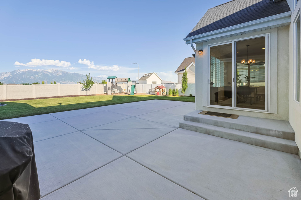 View of patio with a playground, entry steps, and a mountain view