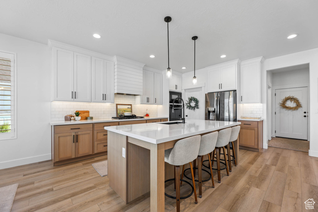 Kitchen featuring stainless steel appliances, light wood finished floors, tasteful backsplash, light countertops, and recessed lighting