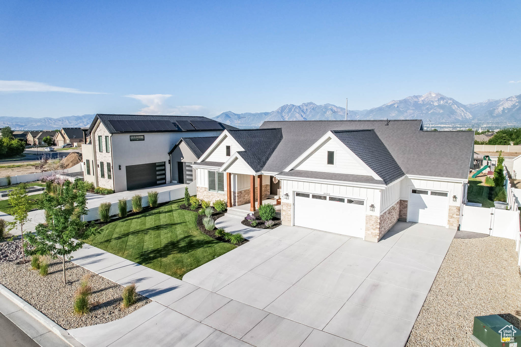 Modern farmhouse featuring an attached garage, a mountain view, driveway, and board and batten siding