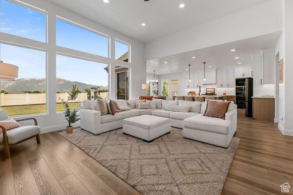 Living area with a mountain view, wood finished floors, recessed lighting, a chandelier, and a high ceiling