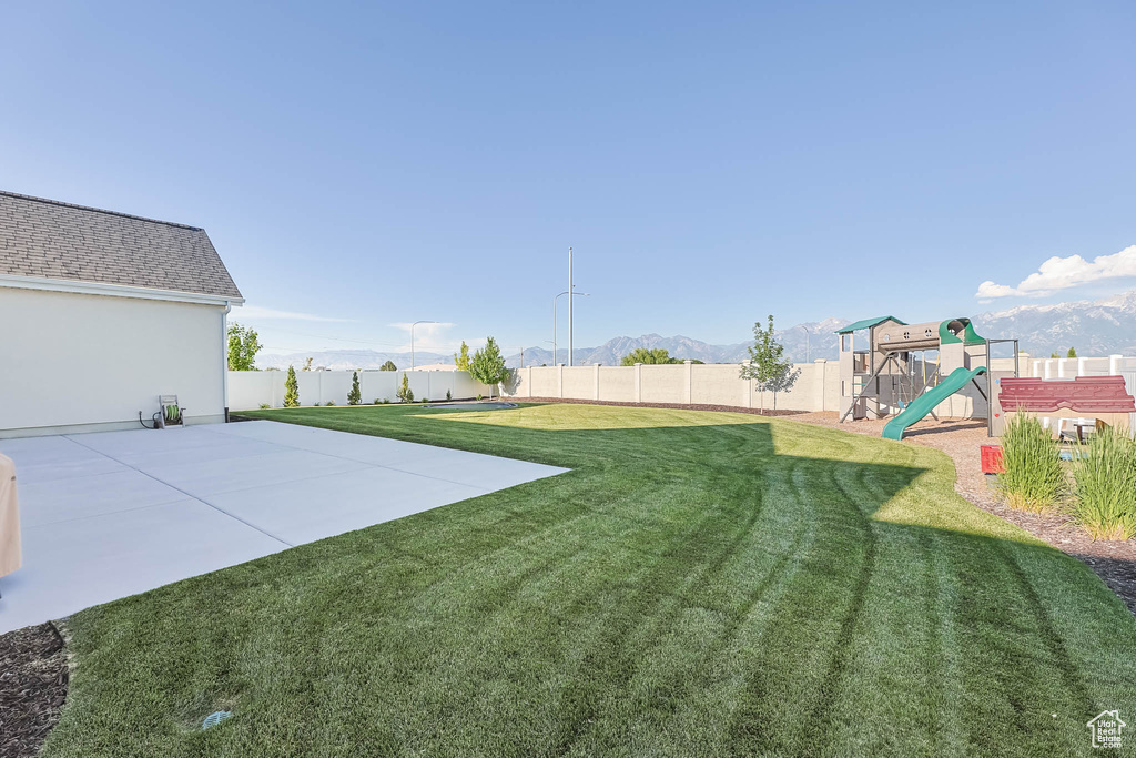 Fenced backyard with a playground, a patio, and a mountain view