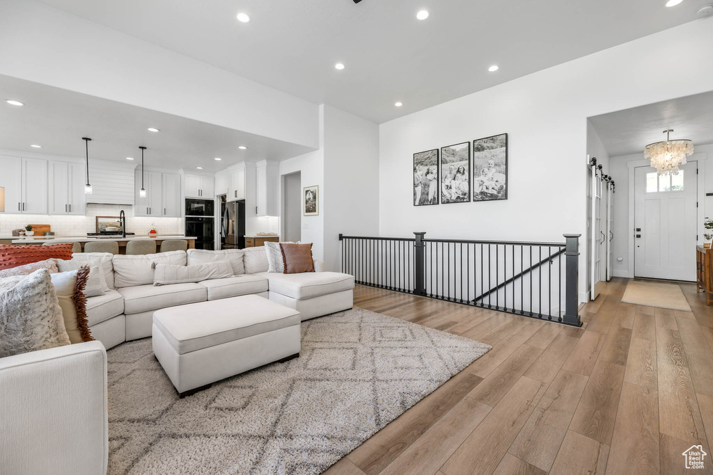 Living room with light wood-style floors, recessed lighting, and a chandelier